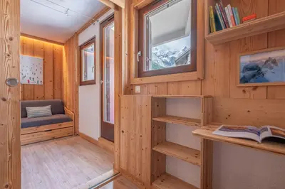 a room with wooden walls and windows and a book shelf at Joli appartement Aiguille du Midi in Chamonix-Mont-Blanc