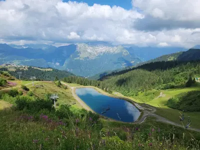 a lake on a hill with mountains in the background at SamoensDt in Samoëns