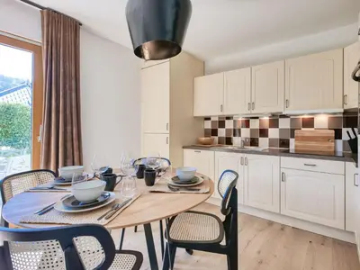 a kitchen with white cabinets and a table with wine glasses at Saint-Gervais : Appartement rénové 2 ch, jardin, WiFi & parking - FR-1-663-34 in Saint-Gervais-les-Bains