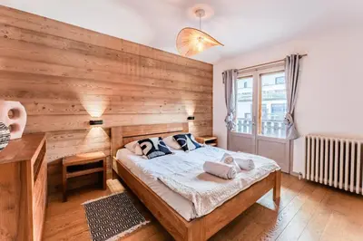 a bedroom with a wooden wall with a bed and a desk at Alpin chic au cœur de Chamonix in Chamonix-Mont-Blanc