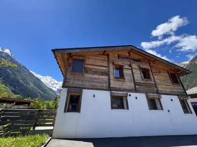 a house with a wooden roof on top of it at Chalet La Frasse in Chamonix-Mont-Blanc