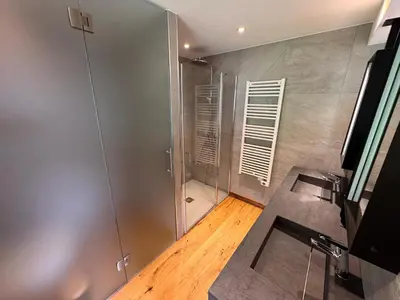 a bathroom with a shower and a wooden floor at Chalet La Frasse in Chamonix-Mont-Blanc