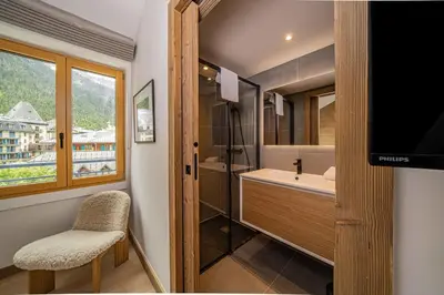 a bathroom with a sink and a shower and a television at Paradisa Penthouse in Chamonix-Mont-Blanc