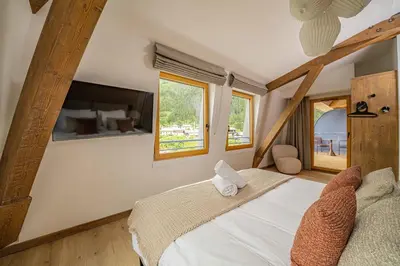 a bedroom with a bed and two windows at Paradisa Penthouse in Chamonix-Mont-Blanc