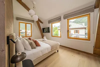 a bedroom with a large bed and two windows at Paradisa Penthouse in Chamonix-Mont-Blanc