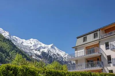 a building with a snow covered mountain in the background at Paradisa Penthouse in Chamonix-Mont-Blanc
