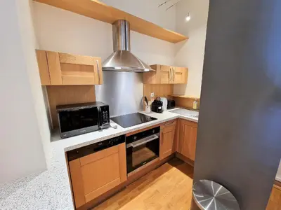 a kitchen with wooden cabinets and a stainless steel appliance at Le Majestic Superbe Appartement Centre Chamonix in Chamonix-Mont-Blanc