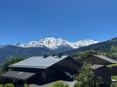 a barn with snow capped mountains in the background at Chalet Taïga face au Montblanc et à 7min de Megève in Combloux