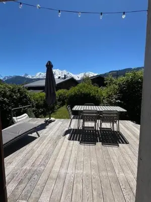 a picnic table and an umbrella on a deck at Chalet Taïga face au Montblanc et à 7min de Megève in Combloux