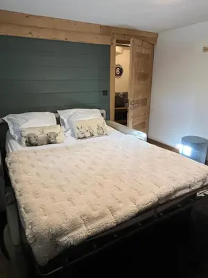 a large bed in a bedroom with a green wall at Chalet Taïga face au Montblanc et à 7min de Megève in Combloux