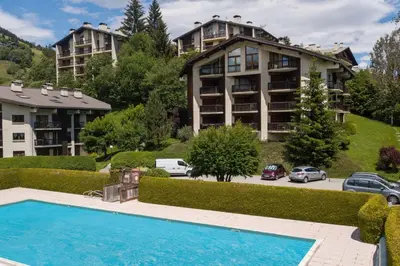 an apartment complex with a swimming pool in front of a building at Les Tulipes Blanches in Megève