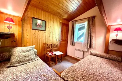 a bedroom with two beds and a window at Les Toits des Cateaux in Combloux
