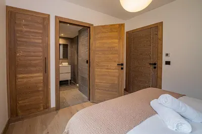 a bedroom with wooden doors and a bed with towels at Paradisa Terrasse Mont-Blanc Central 3-bedroom with Mont-Blanc View! in Chamonix-Mont-Blanc