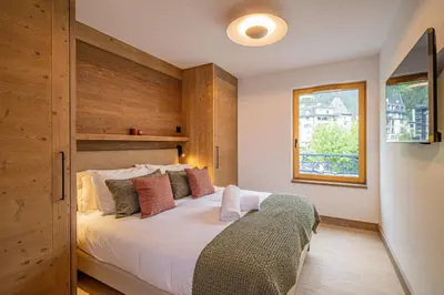 a bedroom with a bed with a wooden wall at Paradisa Mer de Glace Elegant brand new 3-bedroom apartment in Chamonix-Mont-Blanc