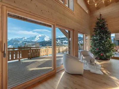 a living room with a christmas tree and a large window at Chalet 180 I Le Chalet Club in Combloux