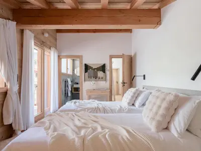 two beds in a bedroom with white walls and wooden ceilings at Chalet 180 I Le Chalet Club in Combloux