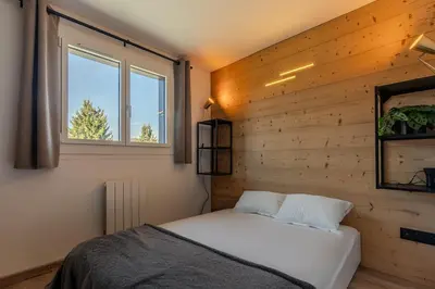 a bed in a room with a wooden wall at Appartement avec superbe vue montagne in Arâches-la-Frasse