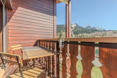 a wooden deck with a wooden bench on a balcony at Appartement avec superbe vue montagne in Arâches-la-Frasse