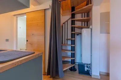a kitchen with a spiral staircase next to a refrigerator at Appartement avec superbe vue montagne in Arâches-la-Frasse