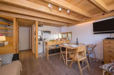 a table and chairs on a balcony with a view of mountains at Résidence Grand Roc - Bruyères 220 - Happy Rentals in Chamonix-Mont-Blanc
