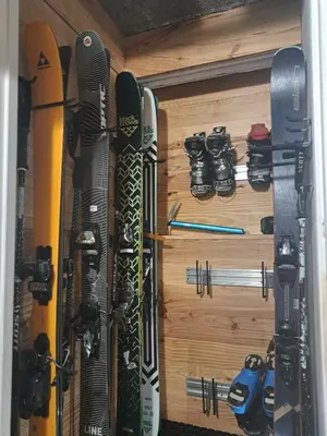 a bunch of skis and snowboards are hanging on a wall at Le Top des Praz in Chamonix-Mont-Blanc