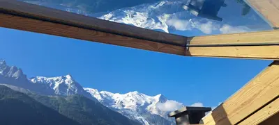 a view of the mountains from inside a window at Le Top des Praz in Chamonix-Mont-Blanc
