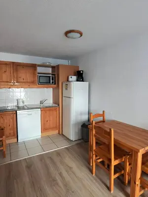 a kitchen with a wooden table and a white refrigerator at Grand Panorama 1 bedroom - sleeps 4, Parking, Pool, Next to Ski Lift in Saint-Gervais-les-Bains
