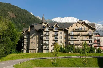 a large apartment building with mountains in the background at Grand Panorama 1 bedroom - sleeps 4, Parking, Pool, Next to Ski Lift in Saint-Gervais-les-Bains