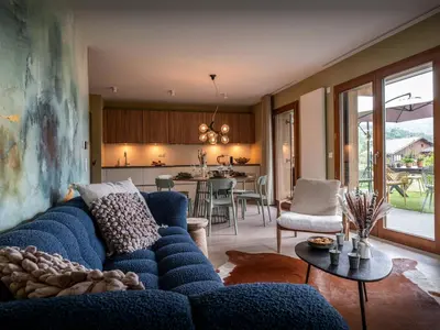 a living room with a blue couch and a kitchen at Lodge Sami - OVO Network in Samoëns