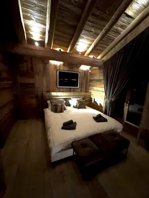 a bedroom with a large white bed and a tv at Chalet de Luxe - Centre-Ville in Megève