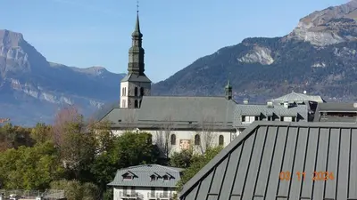 a large white church with a steeple in the mountains at La Comtesse in Saint-Gervais-les-Bains