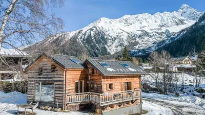 a log cabin with snow covered mountains in the background at Chalet Altiora in Chamonix-Mont-Blanc