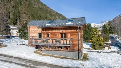 a log cabin with a deck in the snow at Chalet Altiora in Chamonix-Mont-Blanc