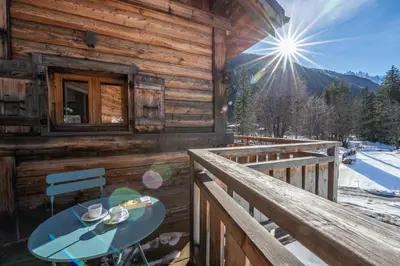 a wooden cabin with a table on the balcony at Chalet Altiora in Chamonix-Mont-Blanc