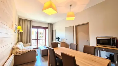 a living room with a table and chairs and a television at Résidence Le Panoramic - Appartement spacieux · Départ et retour skis aux pieds · Piscine · Parking inclus · Spa MAE-3063 in Magland