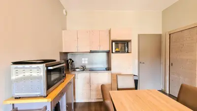 a small kitchen with a table and a microwave at Résidence Le Panoramic - Appartement spacieux · Départ et retour skis aux pieds · Piscine · Parking inclus · Spa MAE-3063 in Magland