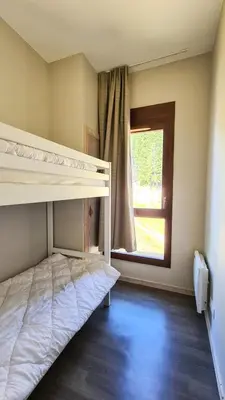 a room with two bunk beds and a window at Résidence Le Panoramic - Appartement spacieux · Départ et retour skis aux pieds · Piscine · Parking inclus · Spa MAE-3063 in Magland