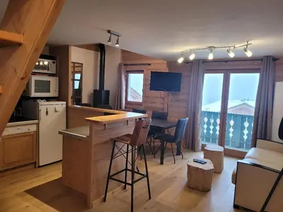 a kitchen with a counter and a table with chairs at Duplex vue sur montagne in Saint-Gervais-les-Bains