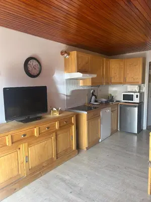 a kitchen with wooden cabinets and a flat screen tv at Cozy apartment in Arâches-la-Frasse