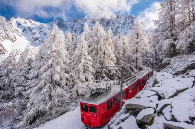 a red train traveling through a snow covered mountain at Chalet Tannuaz - 4 Bedrooms - Quiet area - By Cozee Rentals in Les Houches
