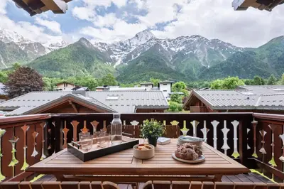 a table on a balcony with a view of mountains at Spacious duplex with terrace in Les Houches in Les Houches