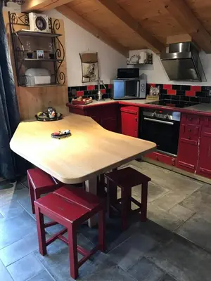 a kitchen with a wooden table and red cabinets at Gite Le sommet in Sallanches