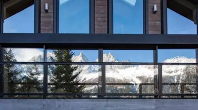 a view of the mountains through the windows of a building at Chalet La Source - Chamonix All Year in Chamonix-Mont-Blanc