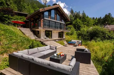 a house sitting on a wooden deck with a couch at Chalet La Source - Chamonix All Year in Chamonix-Mont-Blanc
