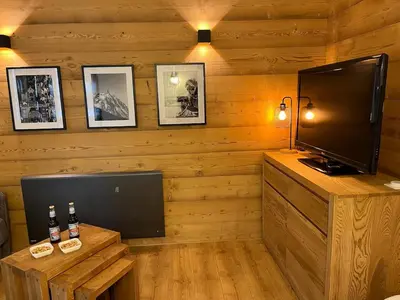a living room with a flat screen tv and a table at Beautiful cozy and fully renovated apartment in Chamonix-Mont-Blanc