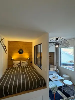 a bedroom with a bed and a living room at Charming studio with balcony in Samoëns