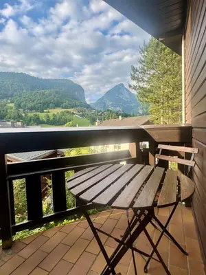 a wooden bench on a balcony with a view of mountains at Charming studio with balcony in Samoëns