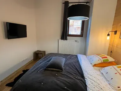 a bedroom with a bed and a flat screen tv at Charmant T2 cabine exposé Ouest avec parking couvert - FR-1-629-148 in Samoëns