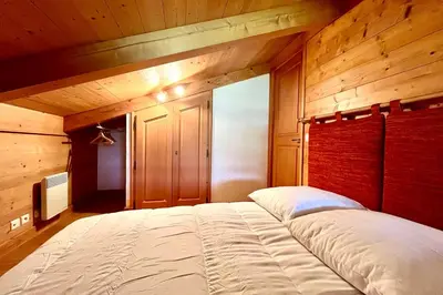 a large bed in a room with wooden walls at Éclat Alpin in Combloux