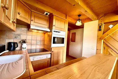 a kitchen with wooden cabinets and a wooden table at Éclat Alpin in Combloux
